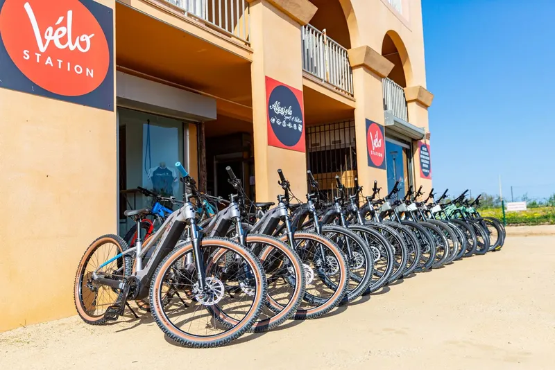 Rangee de velos electriques devant une facade beige et un logo