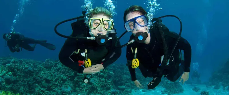 Deux plongeurs souriants avec leur équipement, exploration sous-marine joyeuse