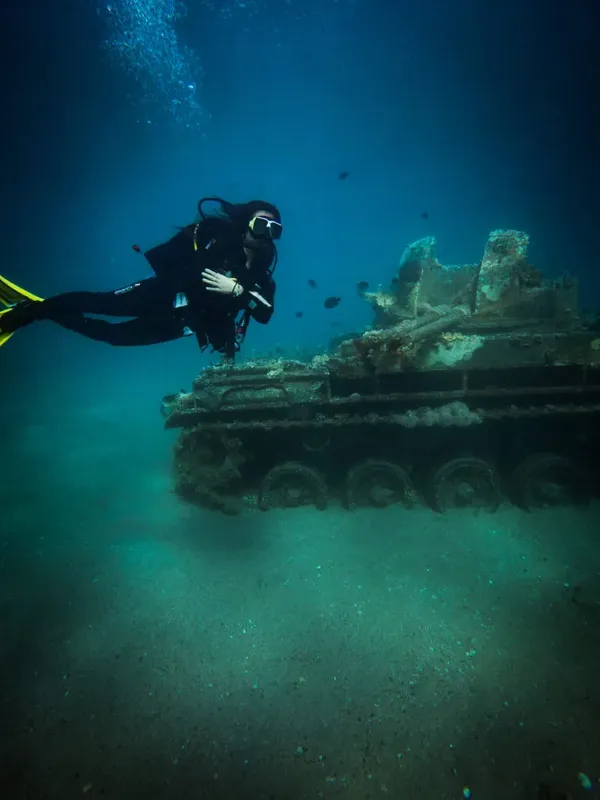Plongeur explorant une épave de char d'assaut au fond marin