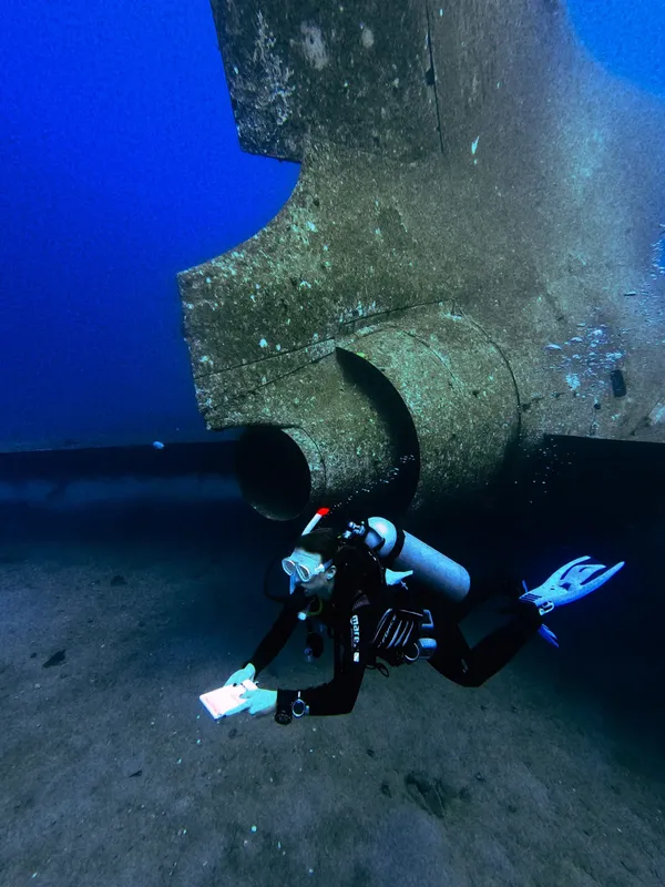 Plongeur explorant une épave sous-marine avec une tablette numérique