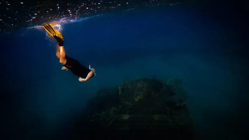 Apnéiste en plongée libre au-dessus d'une structure rocheuse sous-marine