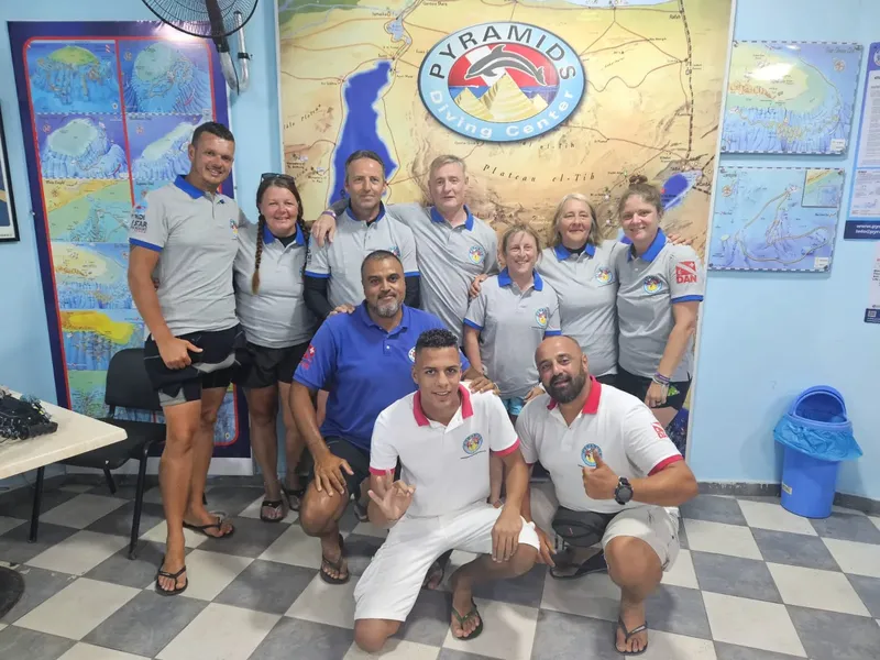 Groupe de personnes souriantes posant devant une carte marine et un logo