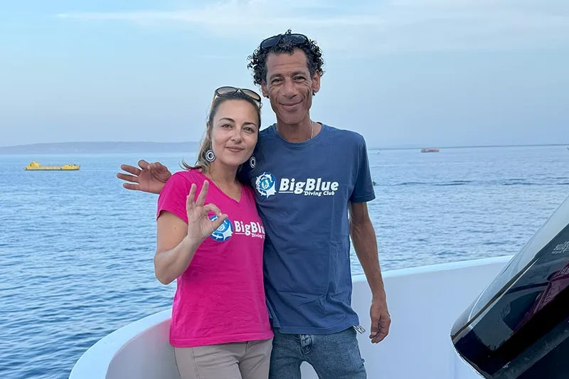 Deux personnes souriantes sur un bateau en mer, signe de la paix