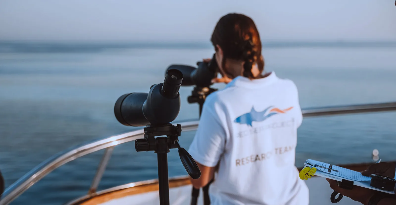Femme observant la mer avec une lunette sur un bateau