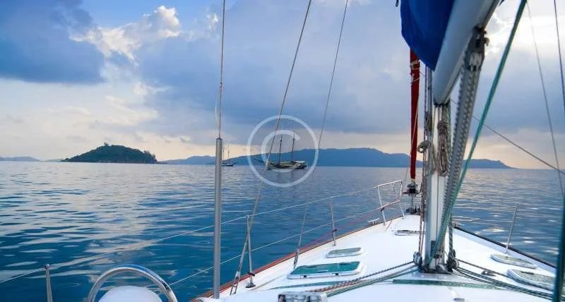 Voilier naviguant sur une mer calme avec une île au loin