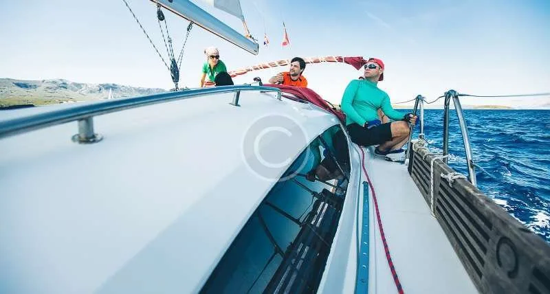 Trois personnes sur un voilier en mer, journée ensoleillée