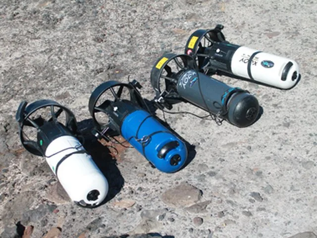 Trois scooters des mers, blancs, bleus et noirs, posés sur un sol
