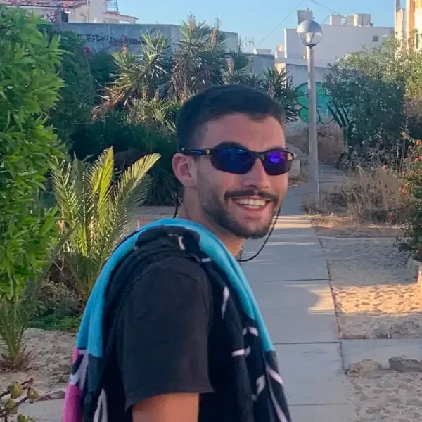 Jeune homme souriant avec des lunettes de soleil et une serviette