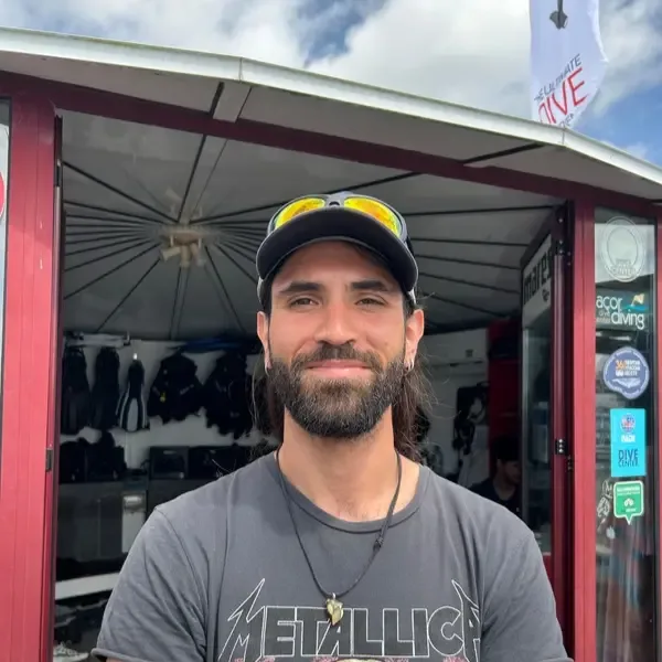Homme souriant devant un centre de plongée avec du matériel visible