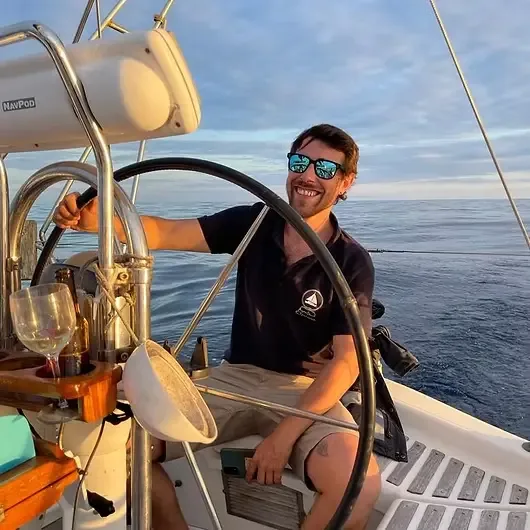 Jeune homme souriant tient le volant d'un bateau en mer