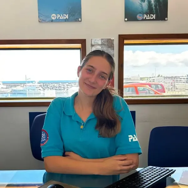Jeune femme souriante assise à un bureau devant des fenêtres