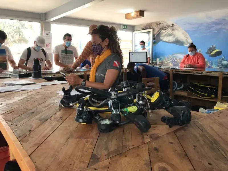 Personnes manipulant du matériel de plongée dans un local lumineux