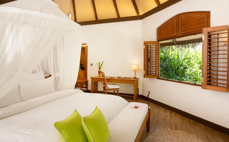 Chambre d'hôtel lumineuse avec lit à baldaquin et vue sur la végétation