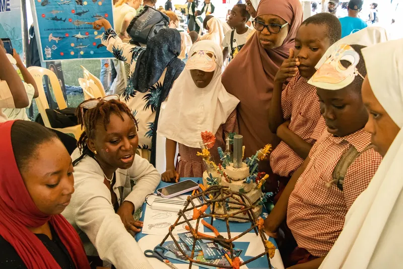 Groupe d'enfants et d'adultes regardent une structure artisanale sur table