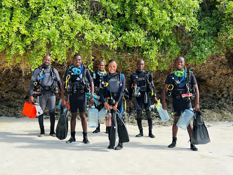 Groupe de plongeurs souriants équipés sur une plage ensoleillée