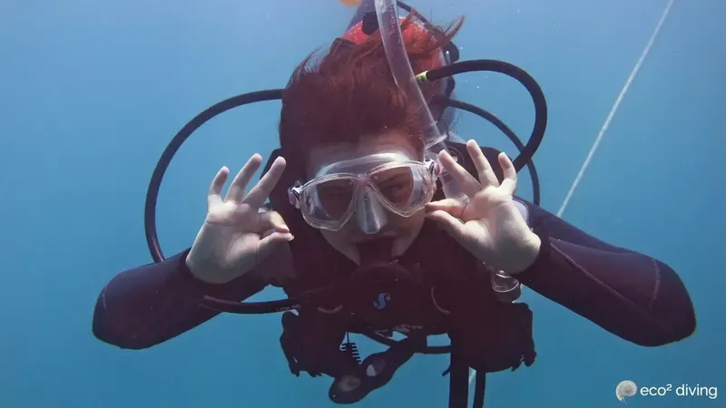 Plongeuse souriante avec masque et gants, geste de célébration sous-marine