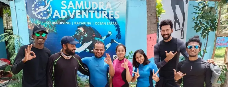 Groupe de personnes souriantes devant une fresque de plongée sous-marine