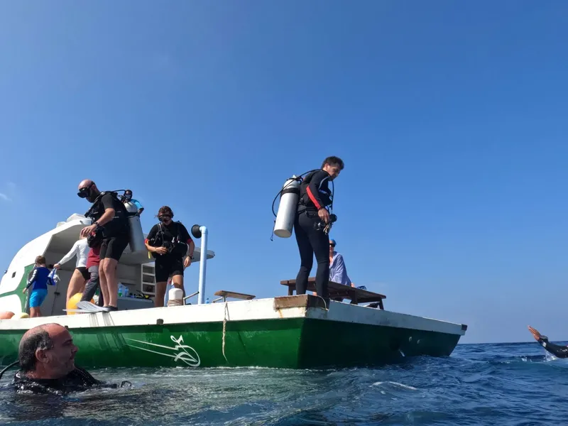 Plongeurs équipés montent à bord d'un bateau vert en mer