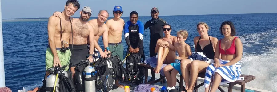 Groupe de plongeurs souriants sur un bateau en mer avec équipement