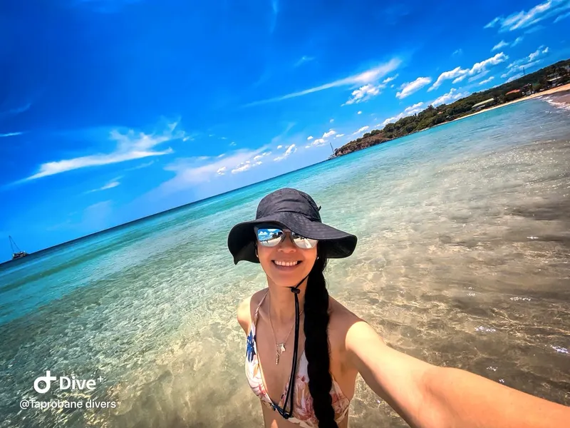 Femme souriante en maillot de bain dans une eau turquoise claire
