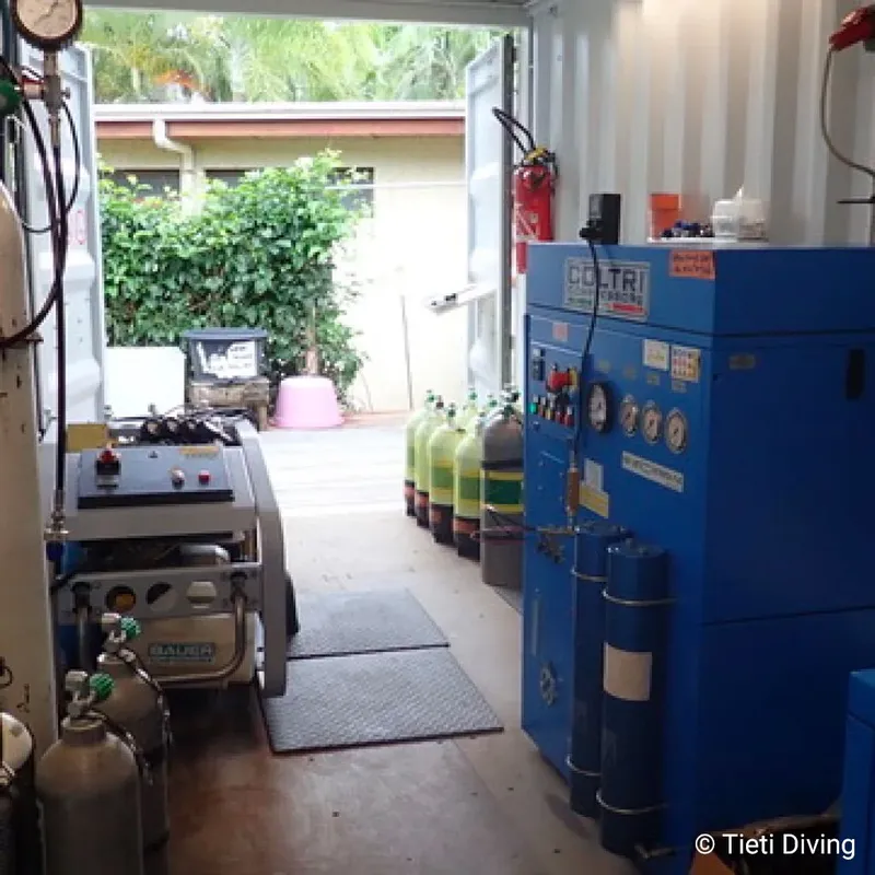 Atelier de remplissage de bouteilles de plongée avec compresseur et rangées de bouteilles