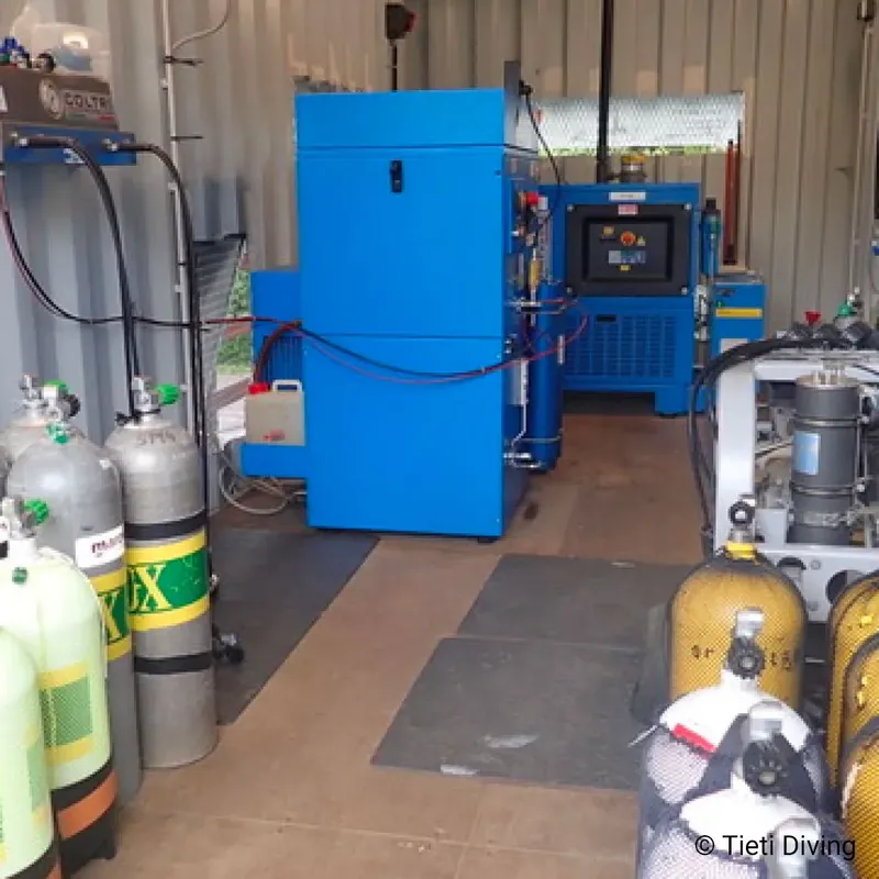 Compresseur bleu et bouteilles de plongée dans un local technique