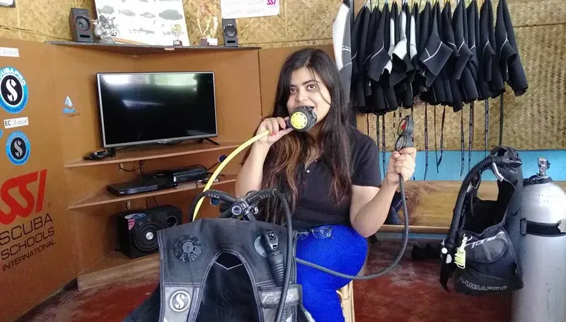 Jeune femme souriante avec détendeur et gilet de plongée
