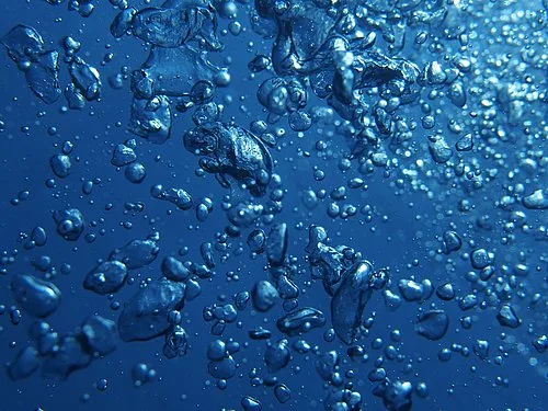 Bulles d'air remontant dans l'eau bleue, lumière diffuse, ambiance aquatique