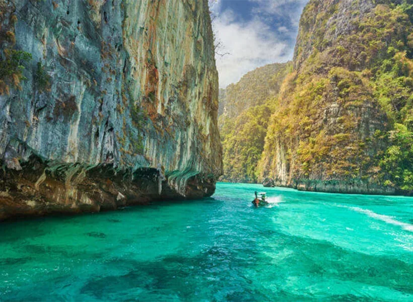Paysage marin avec falaises, eau turquoise et petit bateau rapide