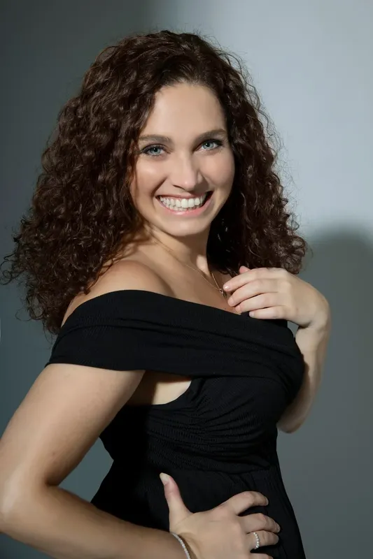 Portrait souriant d'une jeune femme aux cheveux bruns bouclés