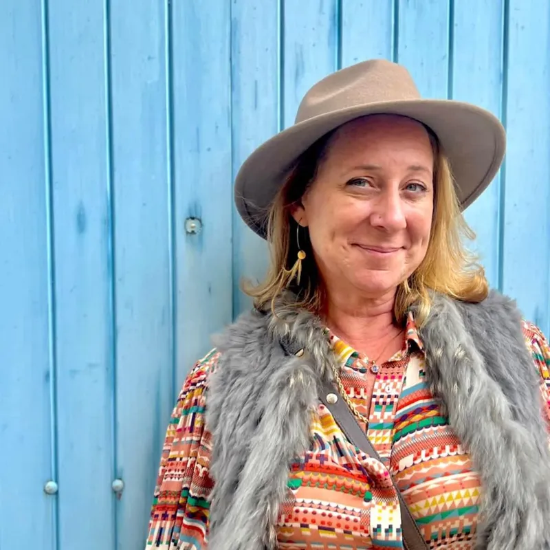 Femme souriante portant un chapeau et un gilet en fausse fourrure
