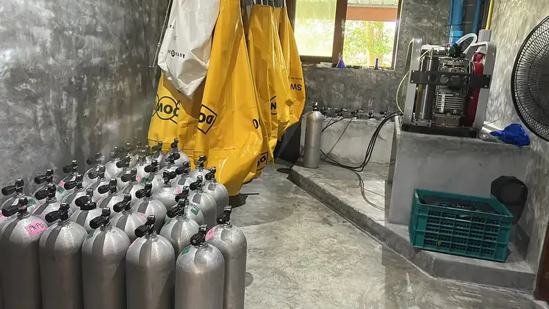 Bouteilles de plongée alignées dans un local avec un compresseur