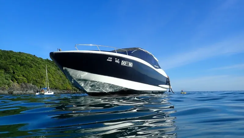 Bateau de plongée noir et blanc sur une mer calme ensoleillée