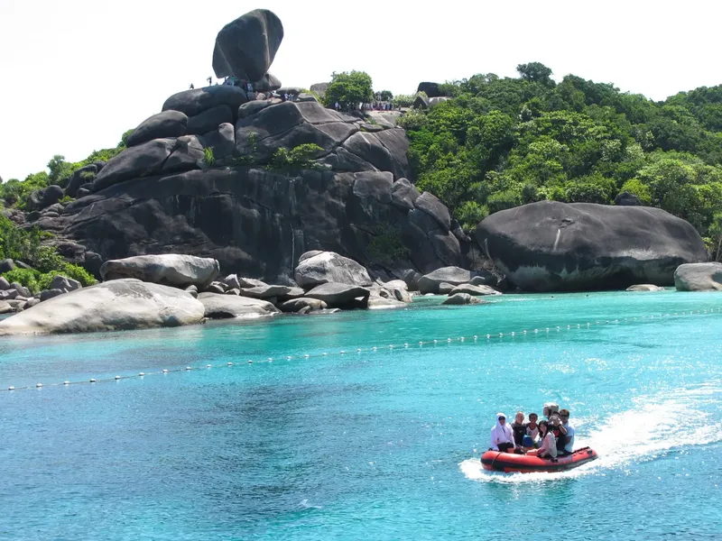 Un bateau pneumatique navigue sur une eau turquoise près d'îlots rocheux