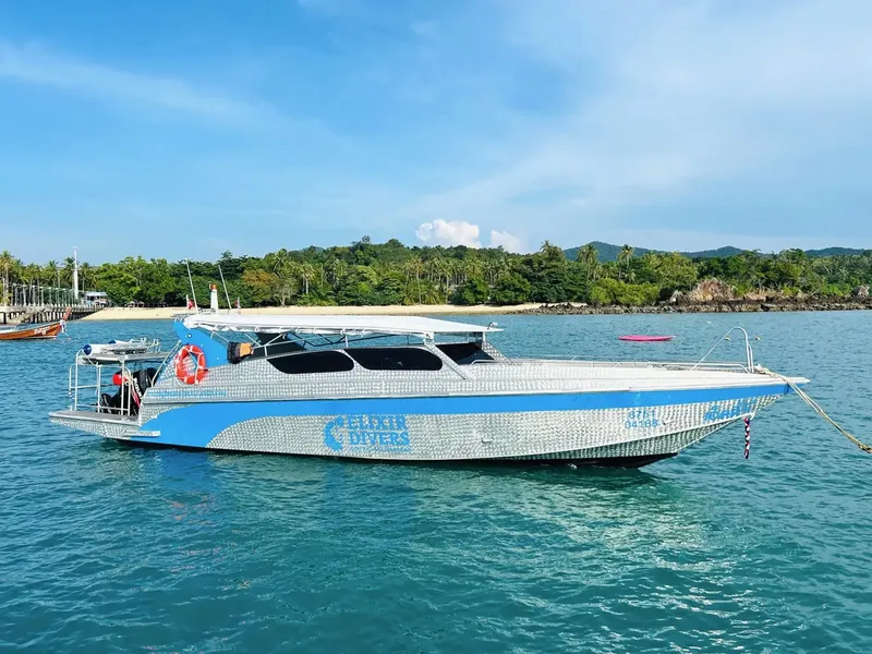 Bateau de plongée argenté sur mer bleue avec île en arrière-plan