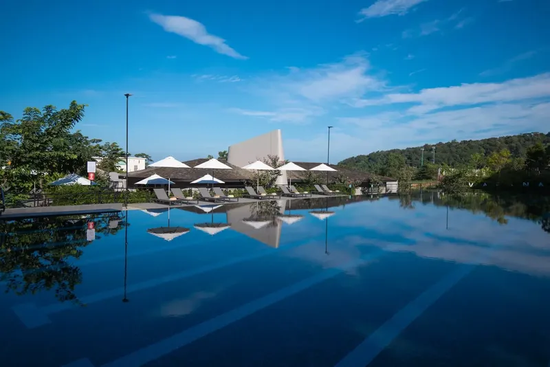 Vue d'une piscine avec des parasols et bâtiments modernes reflétés