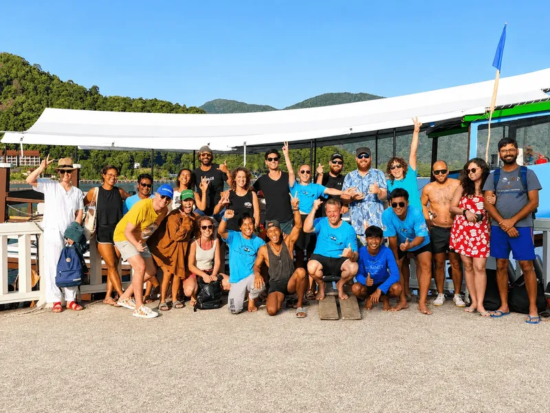 Groupe de personnes souriantes posant devant un bateau et un ponton