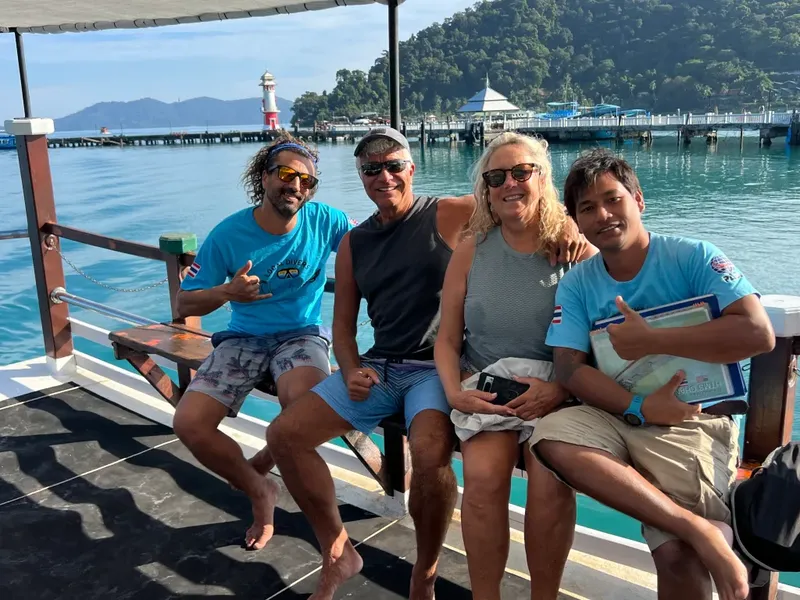 Quatre personnes souriantes sur un bateau en mer, journée ensoleillée