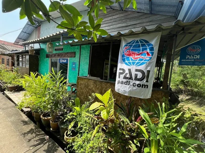 Façade d'un centre de plongée avec enseigne PADI et végétation tropicale