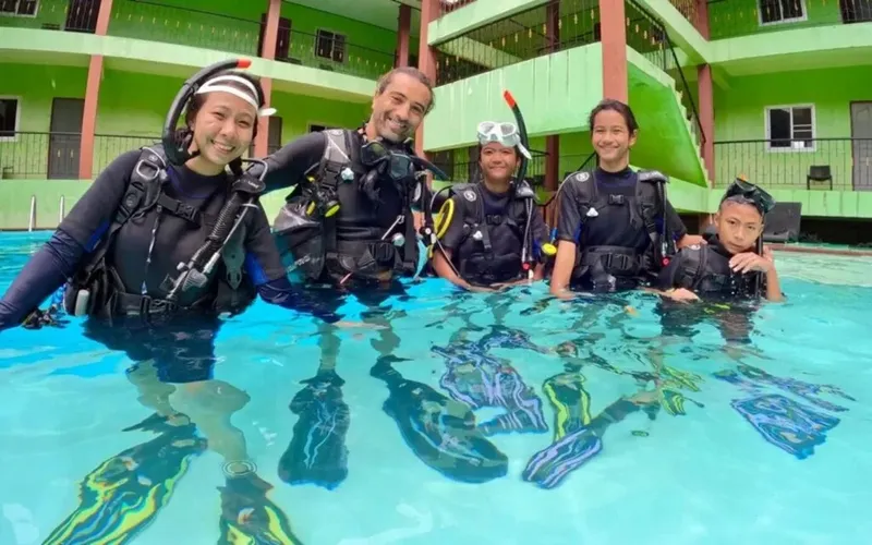 Groupe de plongeurs souriants en combinaison dans une piscine