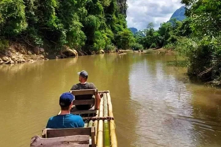 Deux hommes sur un radeau de bambou naviguent sur une rivière