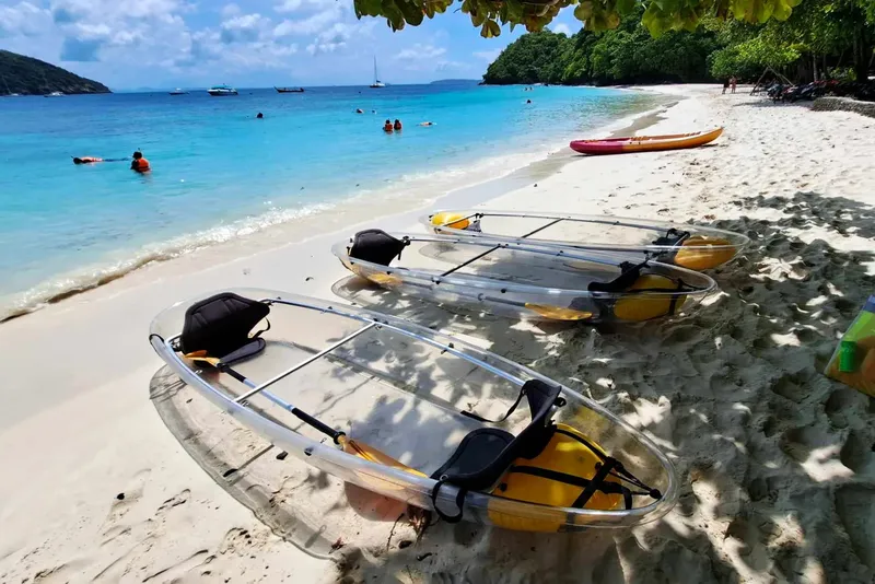 Plage de sable blanc avec kayaks transparents et personnes en mer