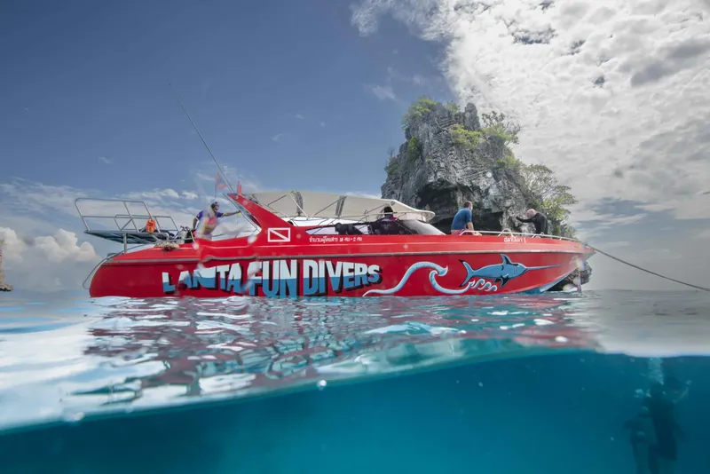 Bateau de plongée rouge avec des personnes à bord, vue mer et sous-marine