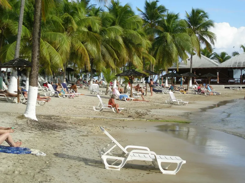 Plage tropicale avec des personnes se relaxant sur des transats blancs