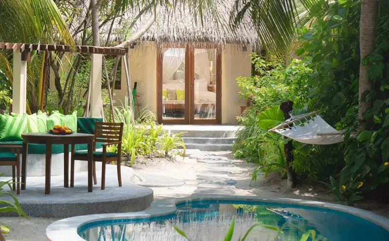Petite maison avec terrasse, piscine et végétation tropicale luxuriante