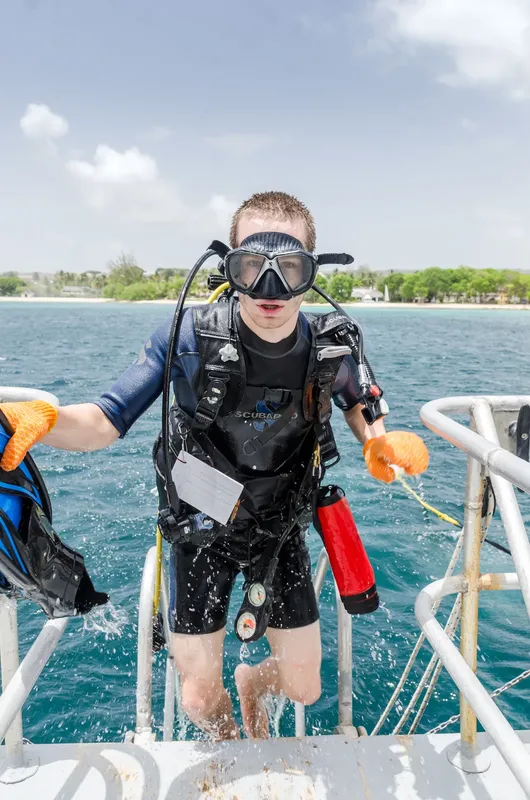 Plongeur équipé sort de l'eau sur un bateau en mer