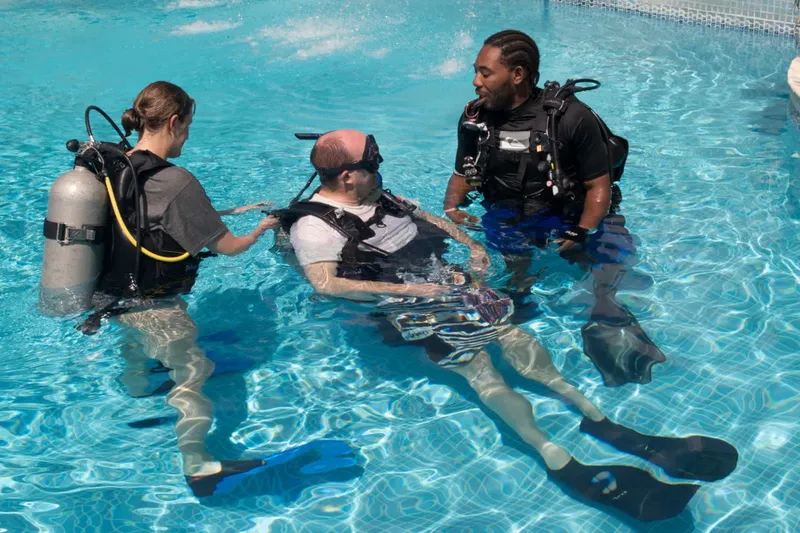 Trois personnes en combinaison de plongée dans une piscine