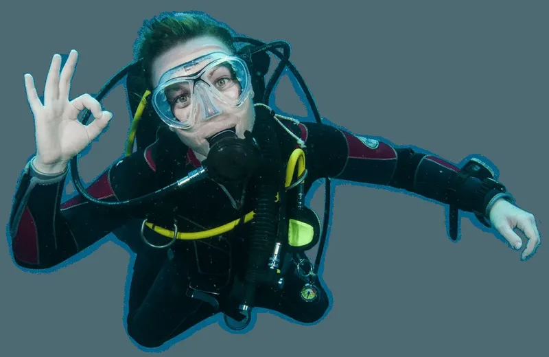 Plongeur avec combinaison et masque faisant un signe OK sous l'eau