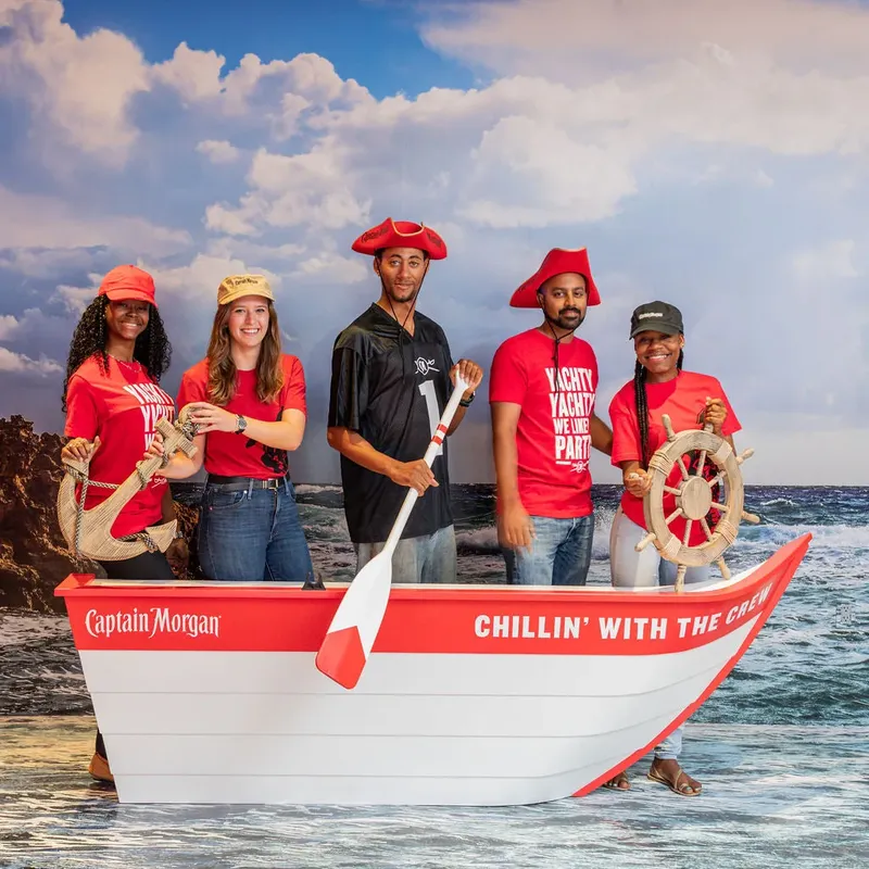Cinq personnes souriantes posent dans un bateau décoré sur fond marin