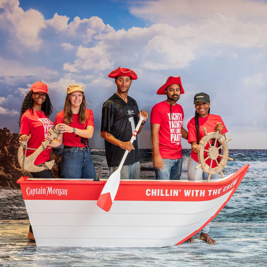 Cinq personnes souriantes posent dans un bateau décoré sur fond marin